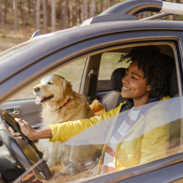 Happy lady driving SUV with a white dog in passenger seat