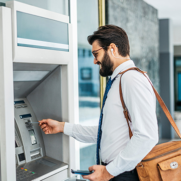 Man in business clothes retrieving money from ATM